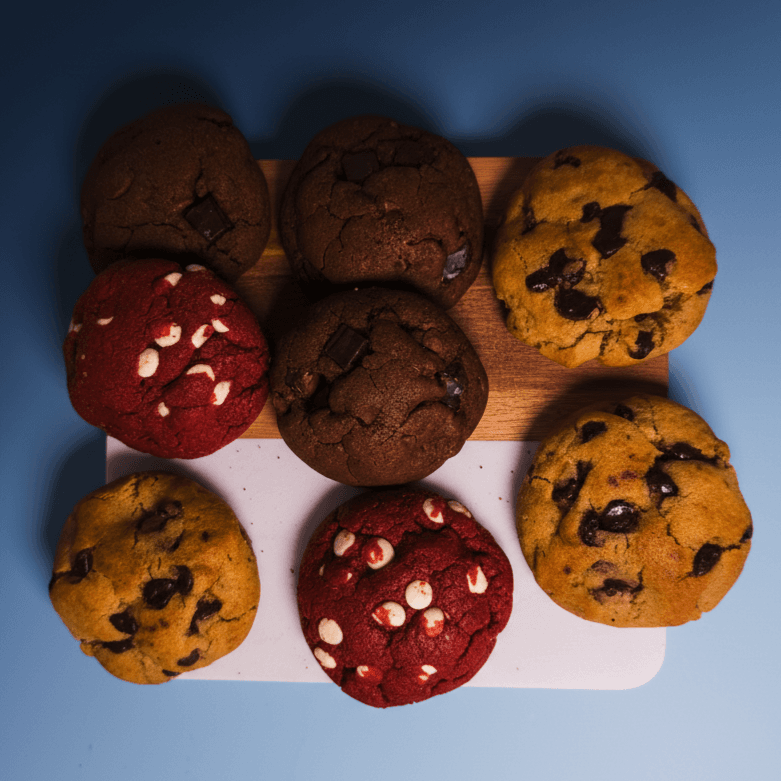 Eight cookies on a white board: chocolate chip, double chocolate, and red velvet